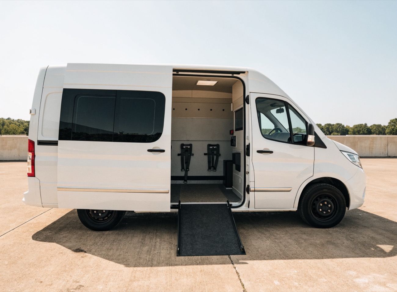 A clean, modern wheelchair-accessible medical transport van with its side ramp deployed and a tidy, professional interior